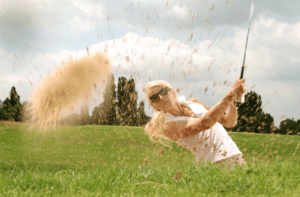 Golfer hitting a shot out of a sand bunker