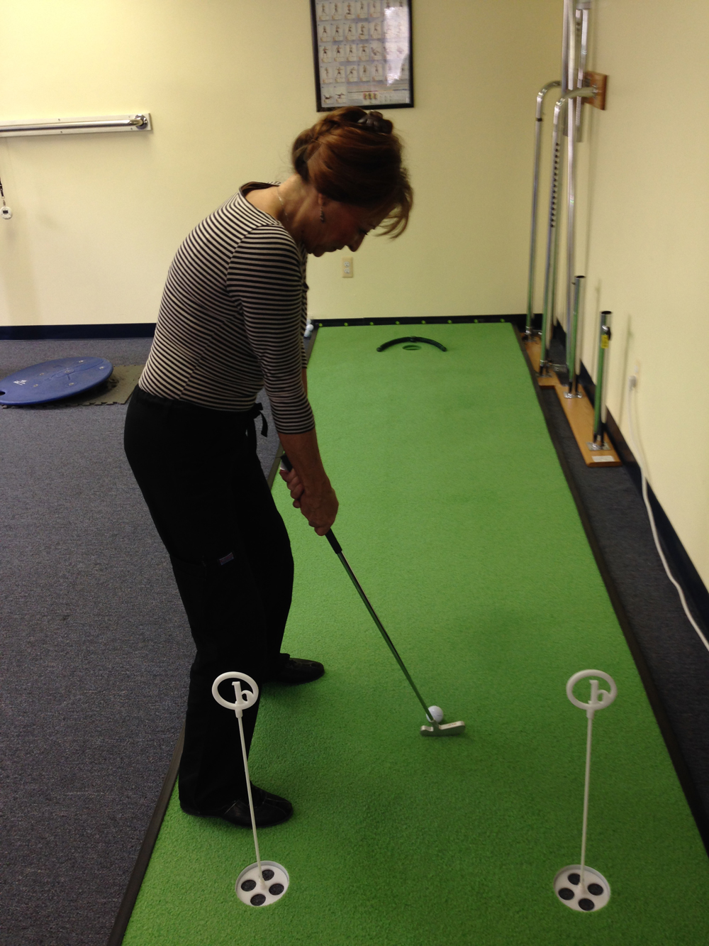 Patient practicing putting on the indoor golf therapy green