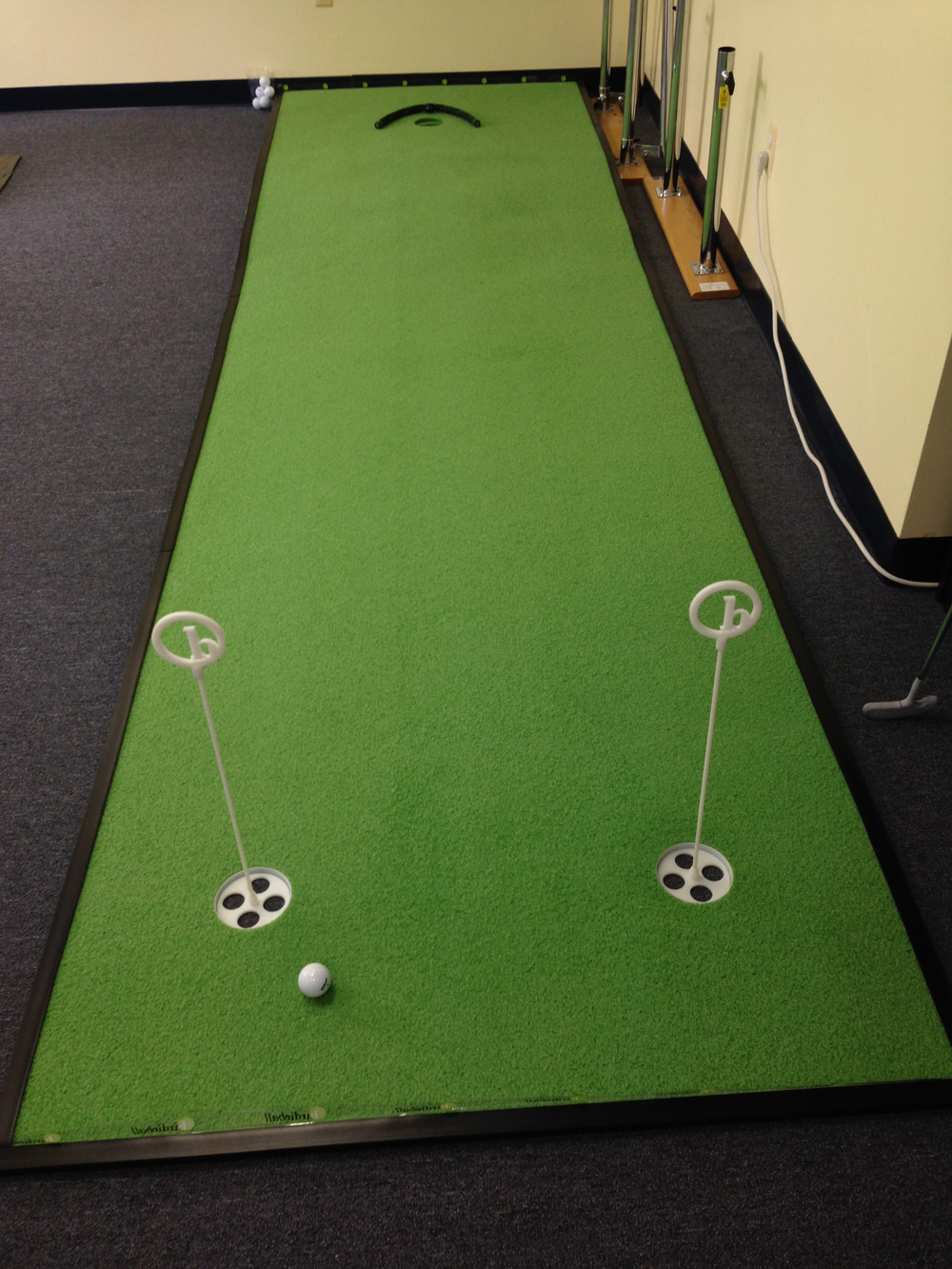 Indoor putting green with practice cups in the golf therapy room