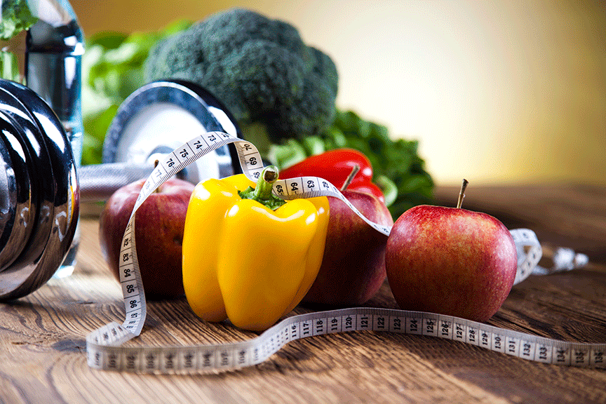 Fresh vegetables, apples, dumbbells and a tape measure representing nutrition and weight loss
