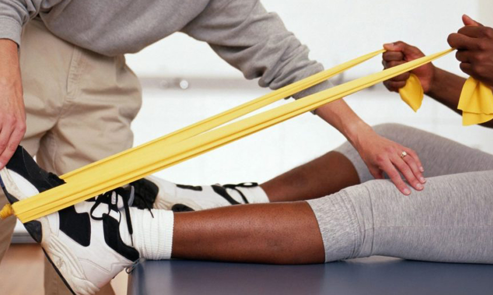 Therapist guiding a patient through a resistance-band leg stretch
